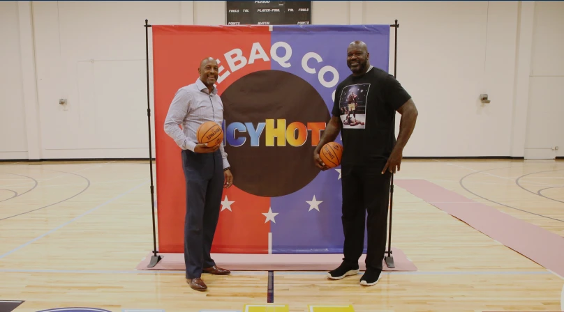 Shaquille O'Neil and Alonzo Mourning standing on the Miami Comebaq Court. Each of them have a basket ball on their right hands.